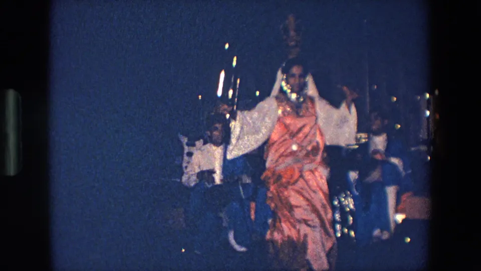 1967 Palermo frame showing the costumed dancer balancing a decorative vessel on her head while musicians and instruments appear behind her.