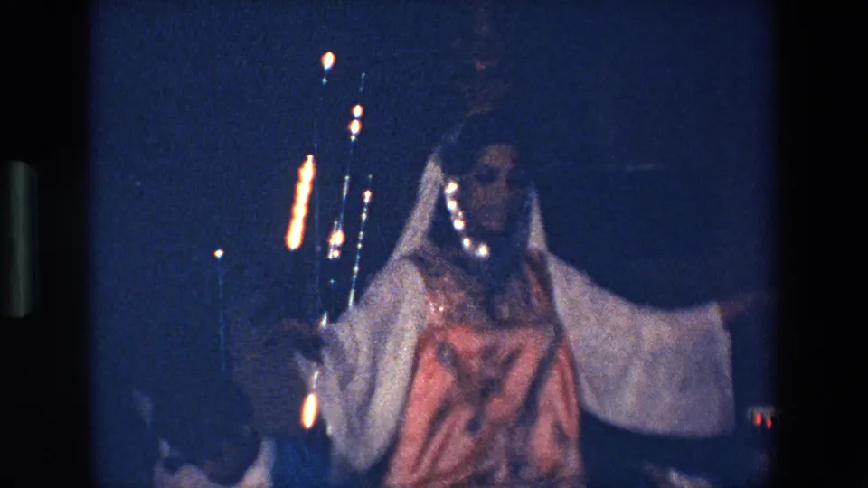 The Palermo dancer stands or turns with one arm extended, wearing a white costume with a brown front panel and balancing the amphora as instruments or musicians remain partly visible behind her.