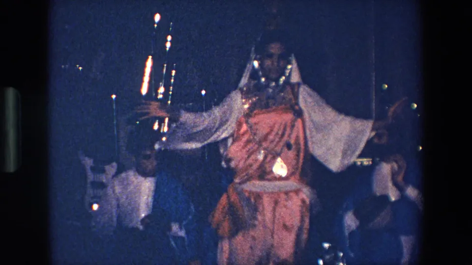 In the supported 1967 Palermo home-movie clip, the dancer remains in motion on a low-lit stage as the band and drum hardware appear around her.