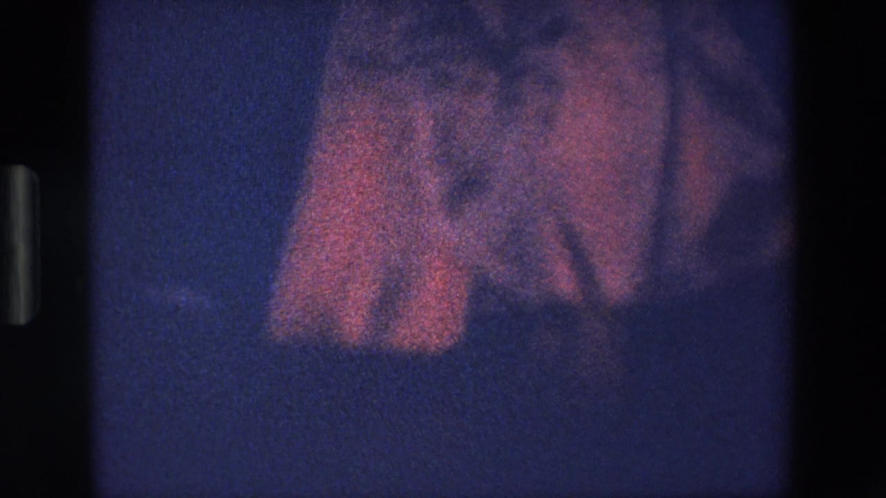 Pink skirt fabric billows above a dark blue foreground in a grainy frame.