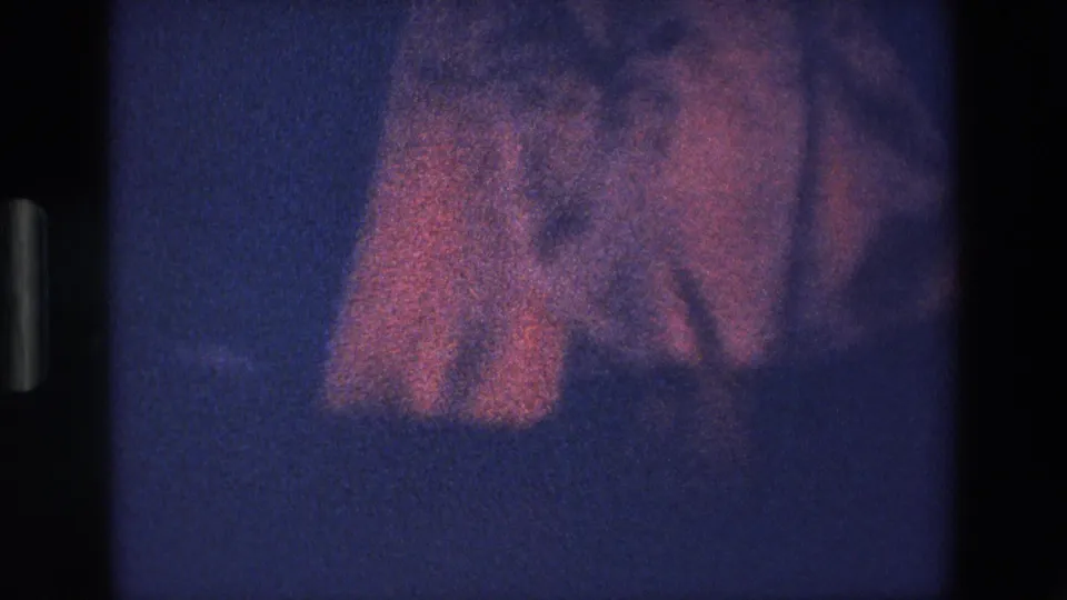 Pink skirt or dress fabric appears to lift in the wind in this 1967 Palermo 8mm home-movie frame, with the person mostly obscured by darkness and grain.