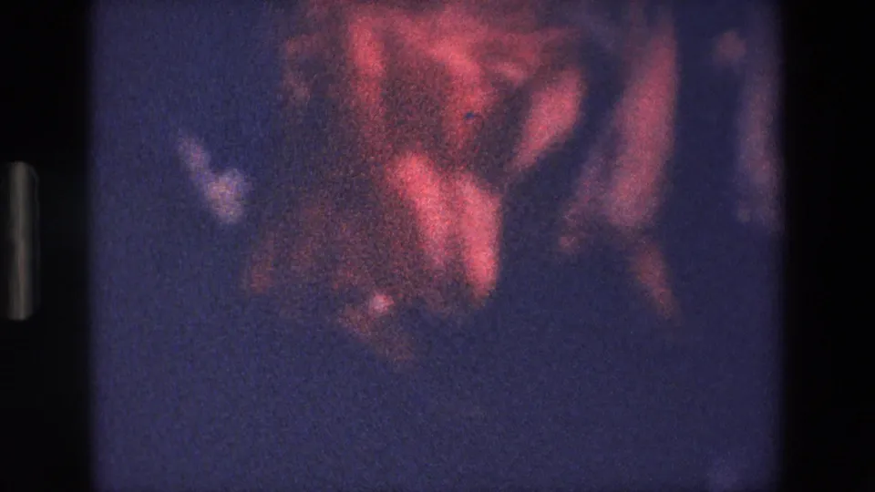 A grainy 1967 Palermo home-movie frame shows indistinct red and shadowed forms, with the subject too soft to identify clearly.
