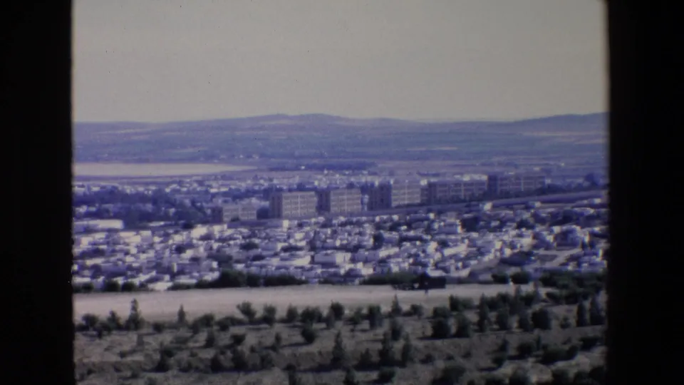 1967 Palermo city view with a dense urban district, larger mid-rise blocks, pale distant hills, and a dark vertical divider from the camera position.