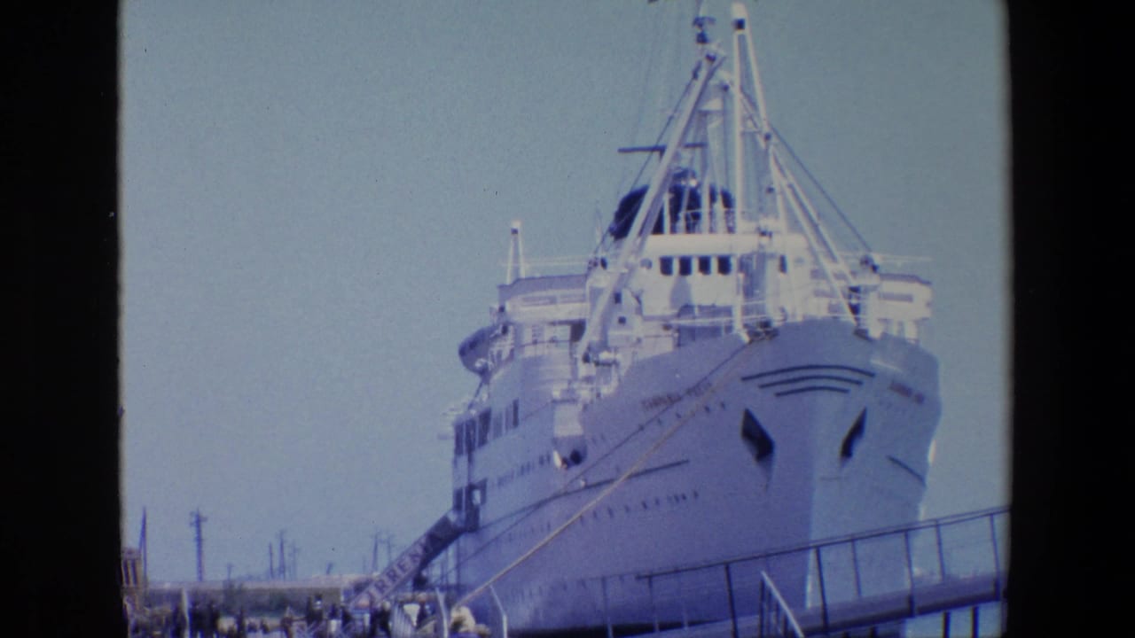 1967 Palermo home-movie frame showing the bow of a large white passenger ship at port, with a gangway, railings, and small figures on the pier.