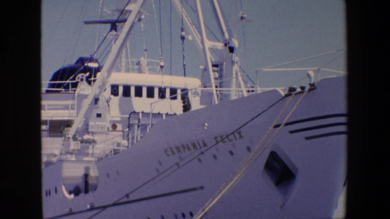 Close 1967 Palermo frame of the Campania Felix bow, with the ship name visible on the hull, deck windows, mast rigging, and mooring lines extending toward the pier.