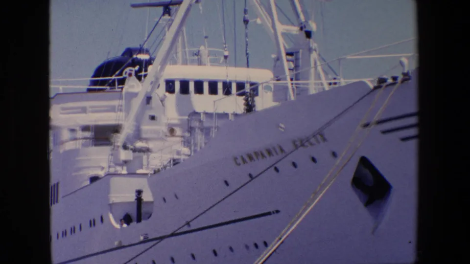 Final 1967 Palermo frame holds on the Campania Felix bow, showing gold-toned hull lettering, dark portholes, rigging, mooring lines, and the ship's upper deck against a clear sky.
