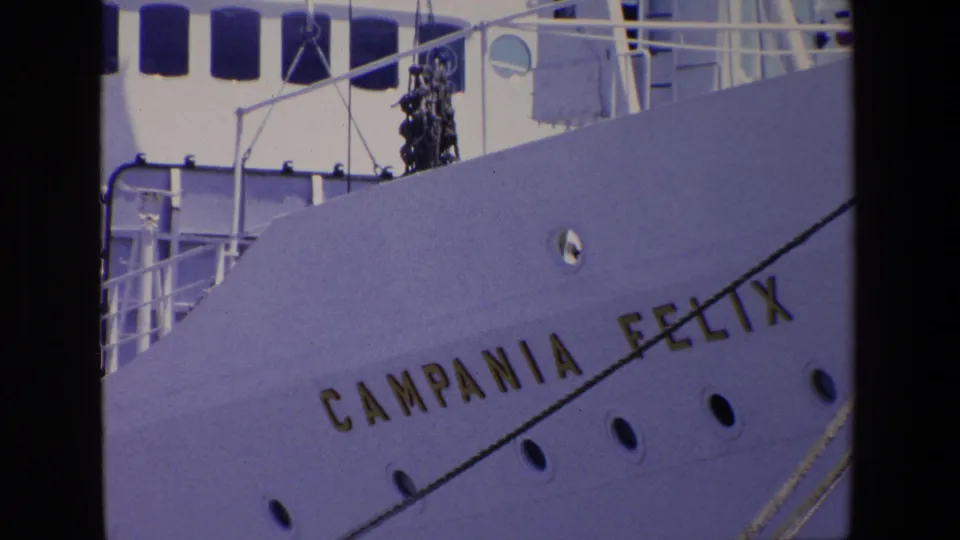 Closer 8mm frame of the Campania Felix hull lettering, with portholes, railings, and part of the upper ship structure visible.