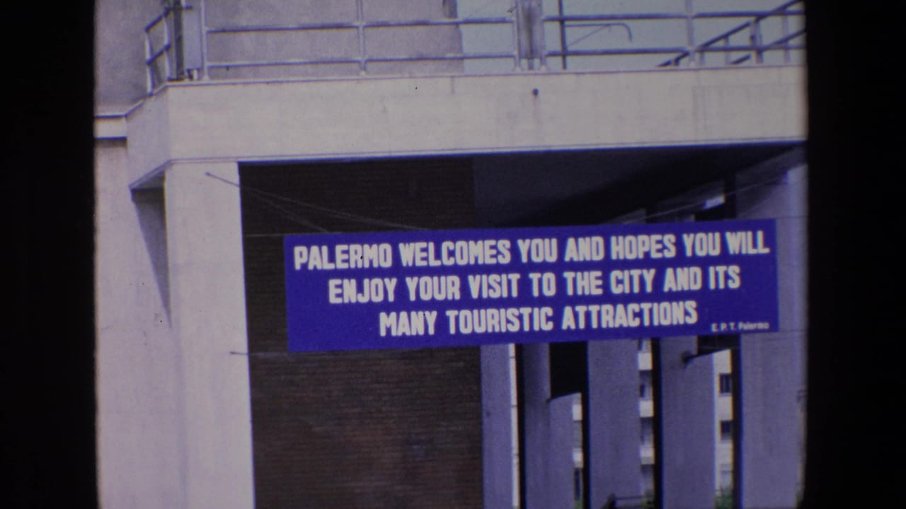 Blue tourist welcome banner framed by concrete columns and shadows.