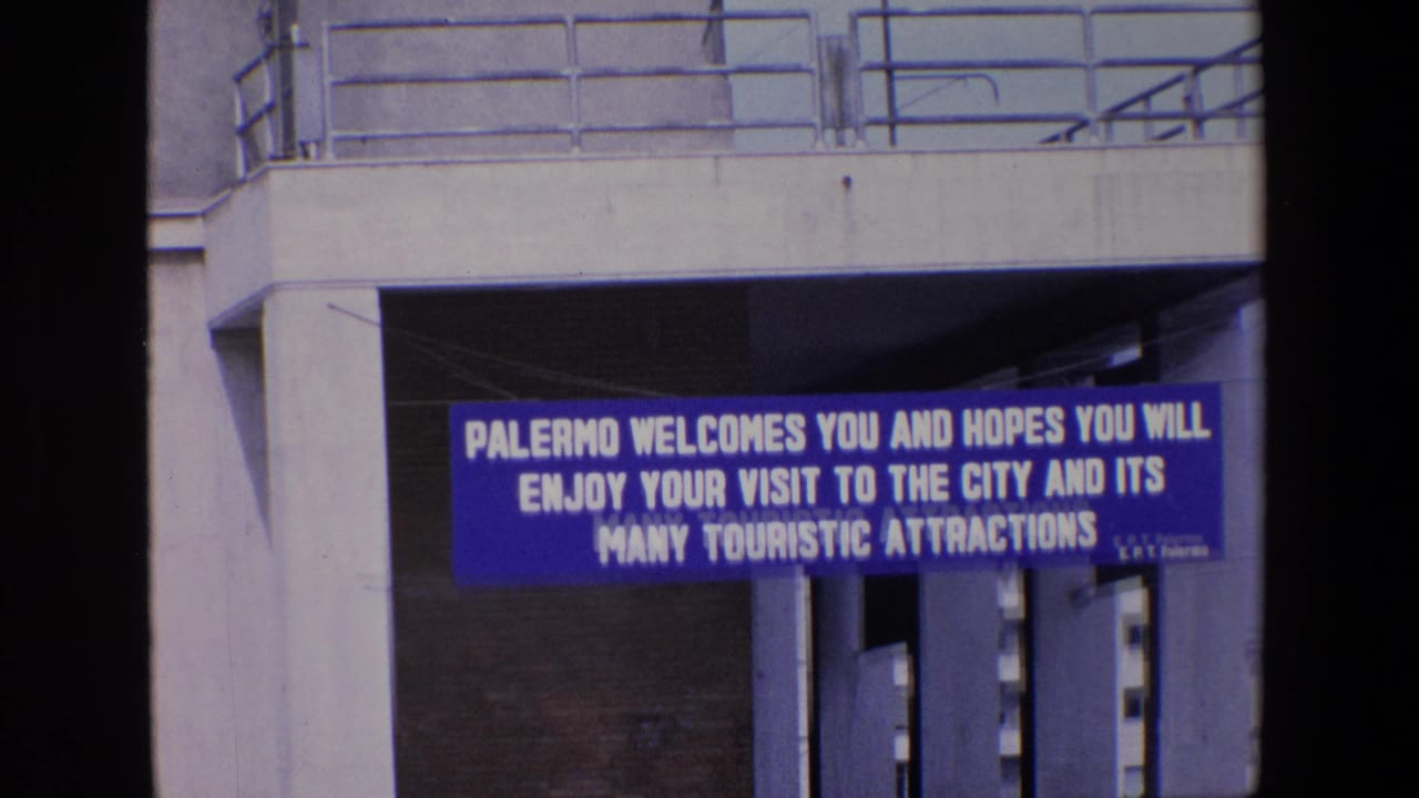 Blue city welcome banner under concrete structure with railings above.
