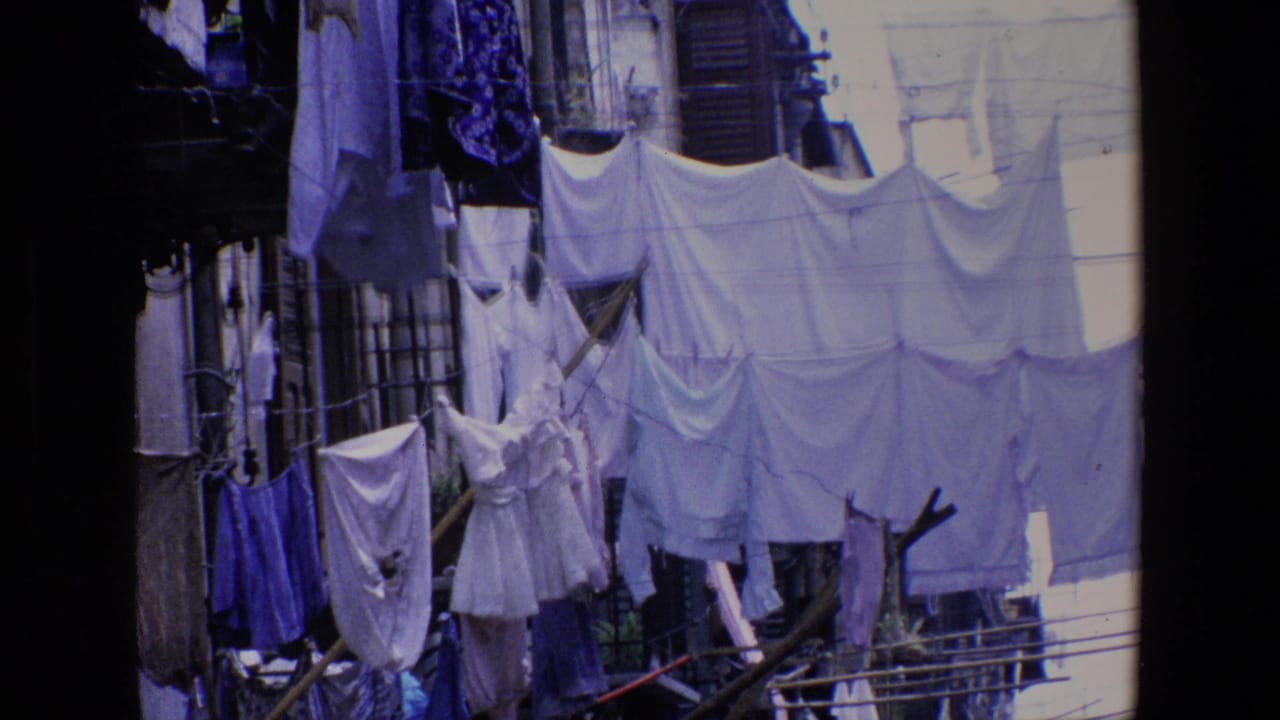 1967 Palermo 8mm frame showing white and blue garments clipped to outdoor clotheslines, seen from a shaded window or balcony edge.