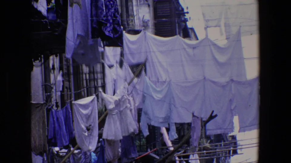1967 Palermo 8mm frame showing white and blue garments clipped to outdoor clotheslines, seen from a shaded window or balcony edge.