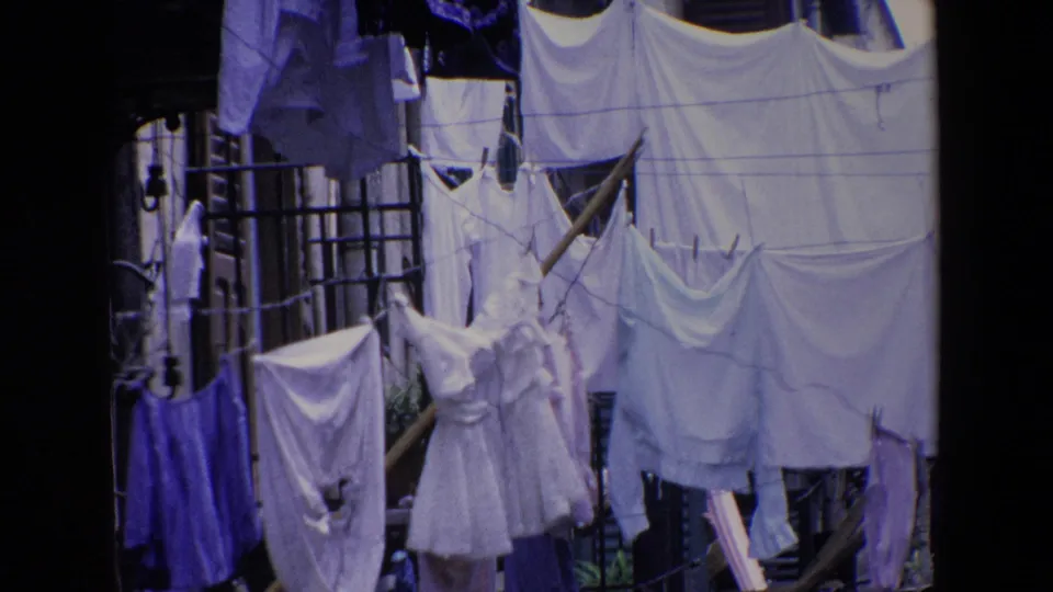 Outdoor laundry in Palermo, Italy, with dresses, shirts, sheets, and clothespins filling the frame in faded 8mm color.