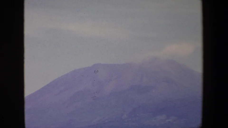 1967 Palermo 8mm frame showing the upper portion of a distant mountain with a faint plume or cloud drifting over the summit area.