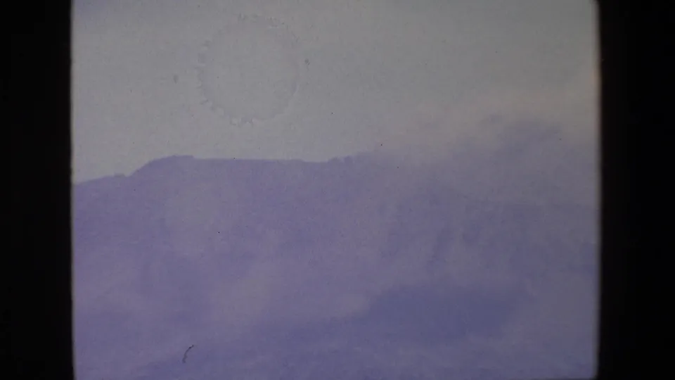 1967 Palermo-area 8mm frame showing a distant mountain ridge softened by fog beneath a pale gray sky.