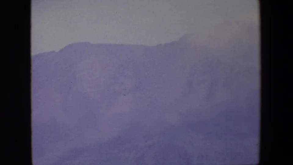 1967 Palermo-area 8mm frame with a purple-gray mountain slope fading into fog under an overcast sky.