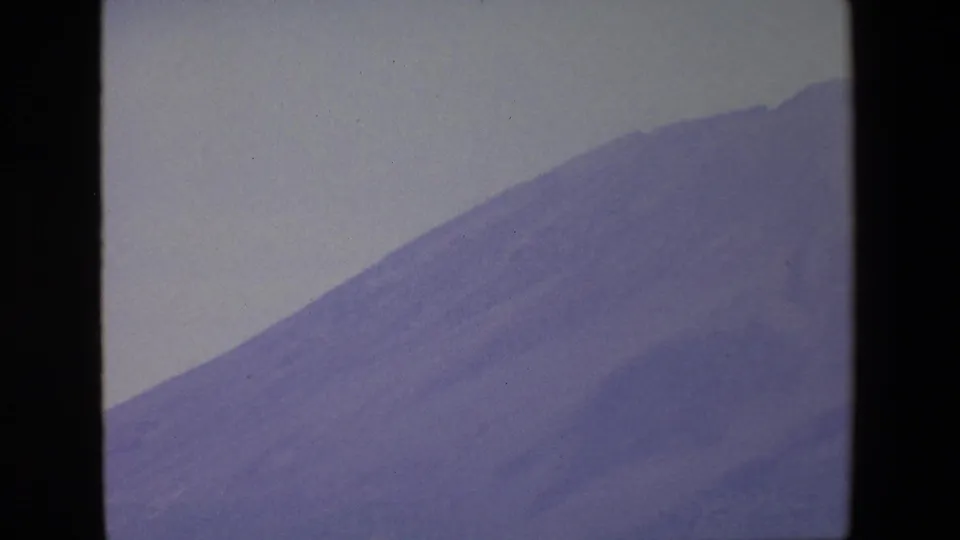 1967 Palermo 8mm frame with a large mountain slope filling the view, bordered by dark window framing and softened by faded color.