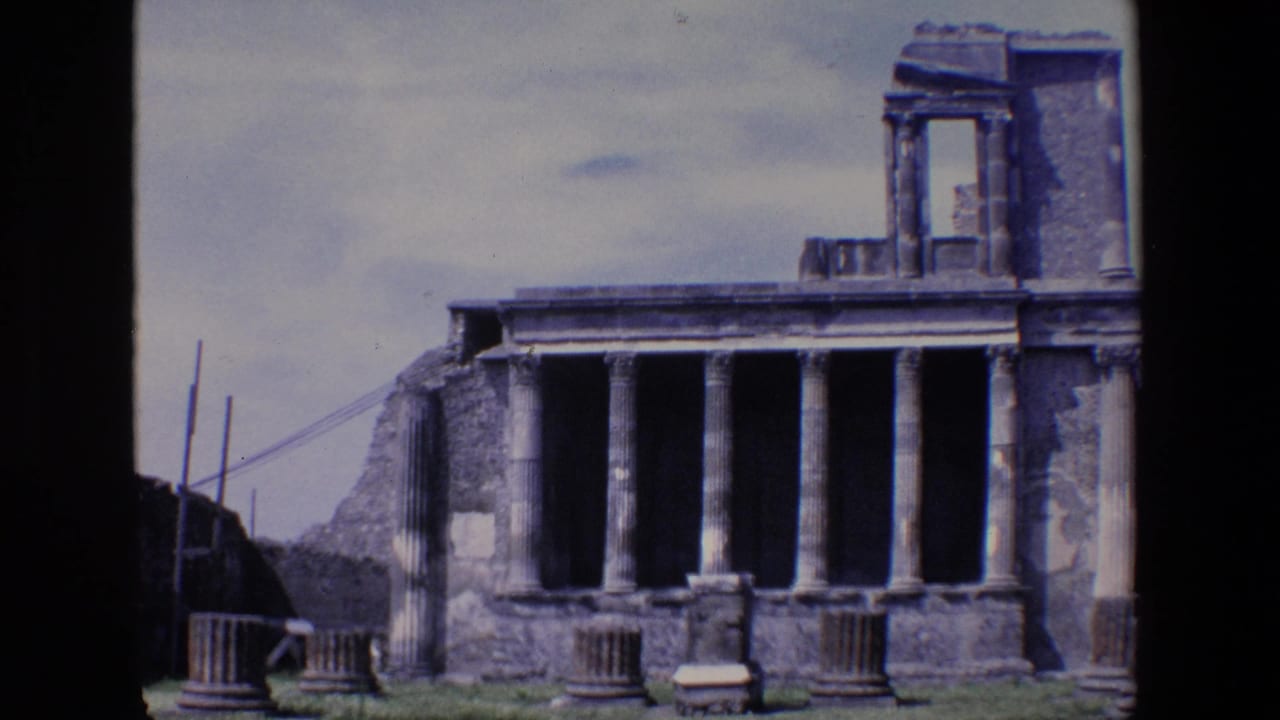 1967 Palermo 8mm frame showing a classical stone ruin with a row of tall columns, crumbling side walls, scattered column pieces, grass, and a pale sky.
