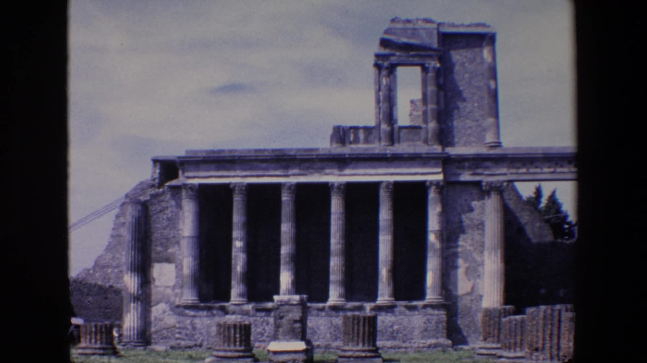 Ruined columned structure with broken masonry, grass foreground, and dark 8mm frame edges.