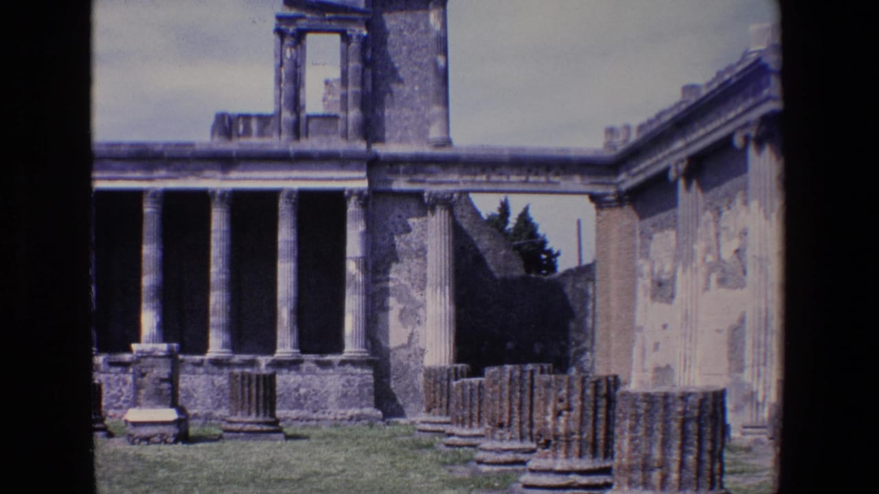 1967 Palermo home-movie frame showing weathered classical columns, ruined walls, grass, and a partly standing stone structure under a bright sky.