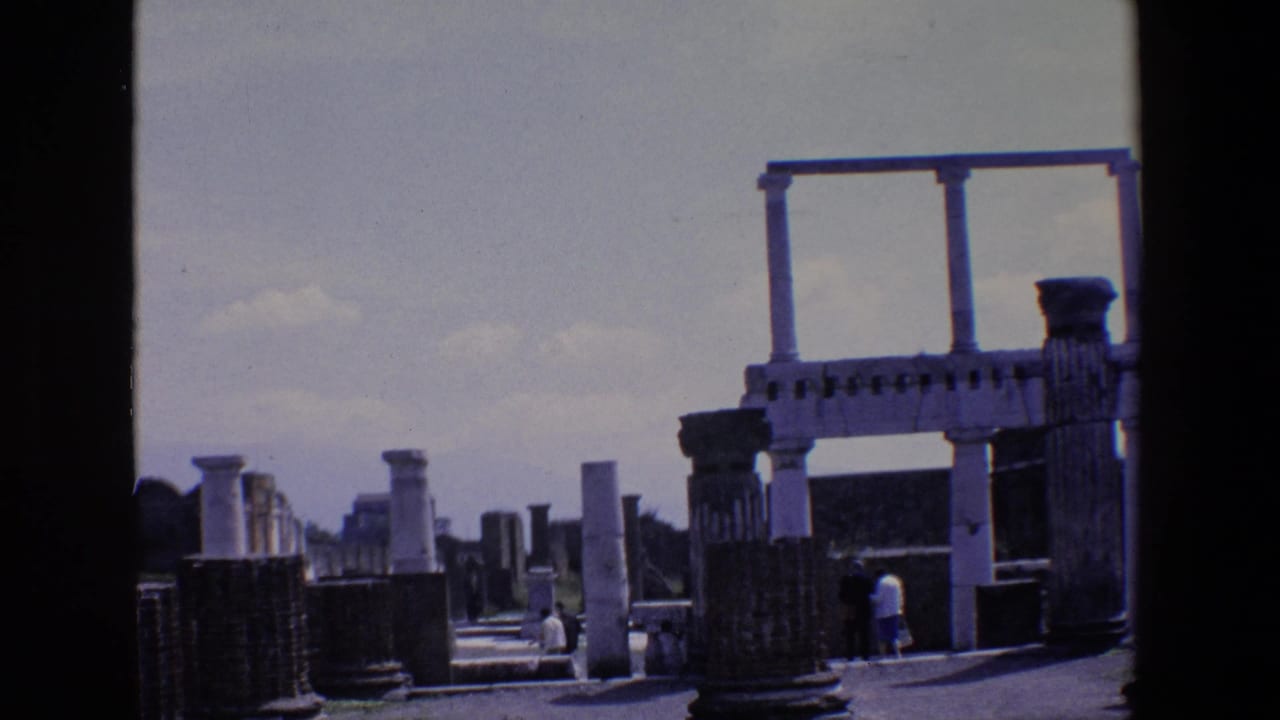Open ruin walkway with columns, partial arch structure, and distant visitors.