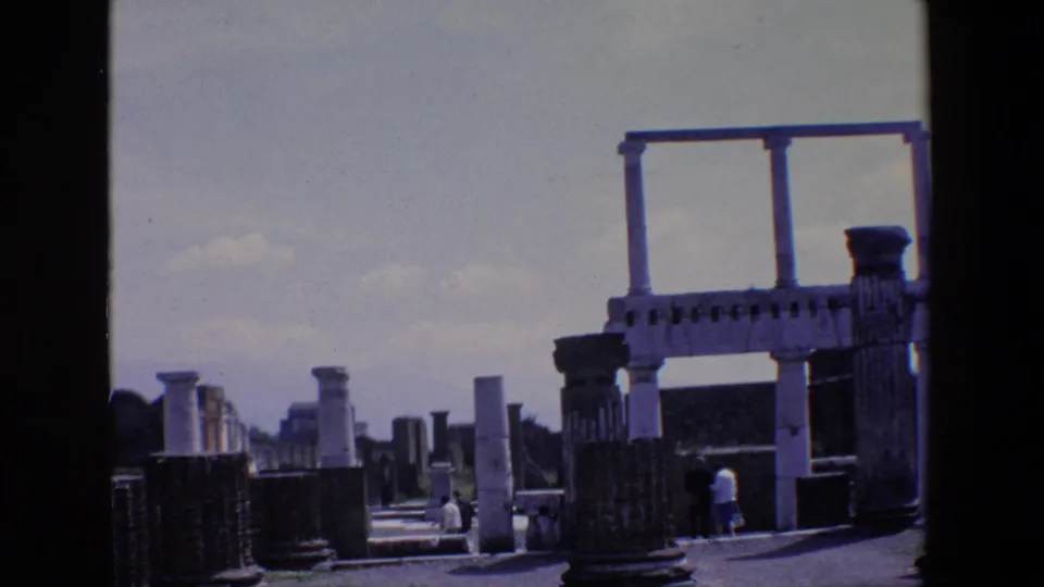 1967 Palermo frame showing an open archaeological walkway with standing columns, a fragmentary arch-like structure, and small visitors in the distance.