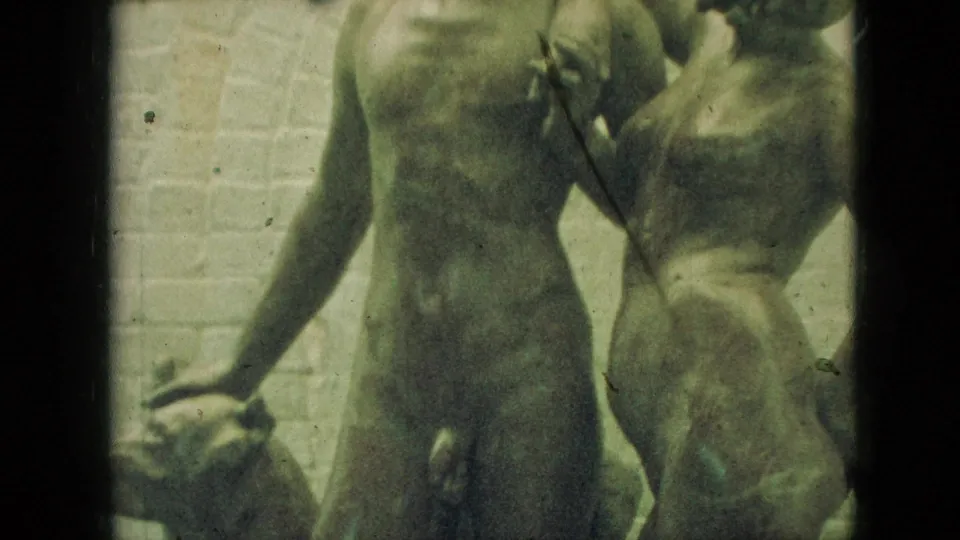 1968 Branson, Missouri frame showing concrete nude figure sculptures near a pale block wall, rendered with grain, dust, and greenish 8mm color shift.