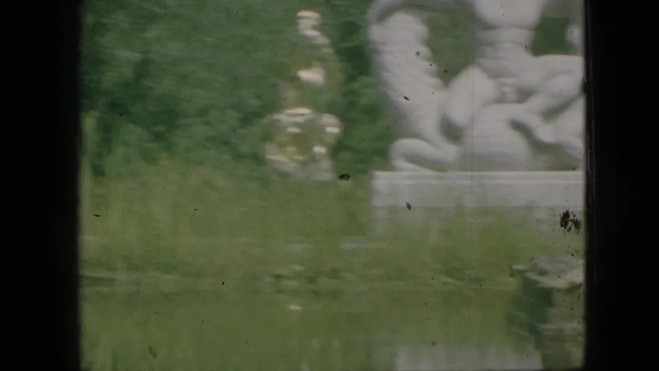 A pale classical-style figure statue on a pedestal appears beside foliage and a pond or reflective water area in the 1968 Branson park scene.