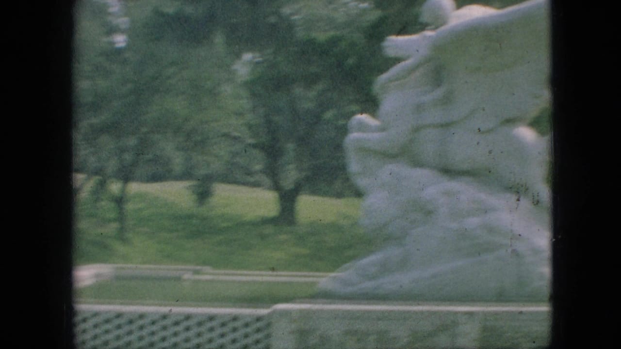 1968 Branson, Missouri 8mm frame showing a white horse-and-rider stone sculpture near a park lawn and trees, with dark film borders visible.
