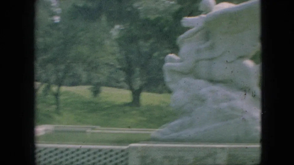 1968 Branson, Missouri 8mm frame showing a white horse-and-rider stone sculpture near a park lawn and trees, with dark film borders visible.