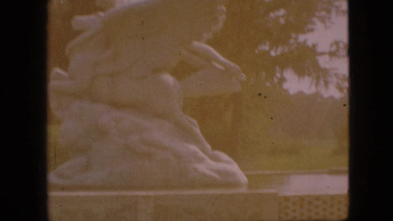 Closer faded view of the horse-and-rider sculpture with trees behind it.