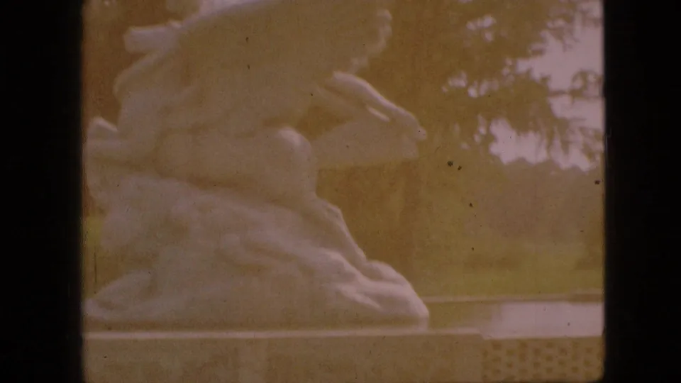 Faded 1968 Branson, Missouri 8mm view of the white horse-and-rider sculpture, seen closer with trees and park background softened by warm color shift.