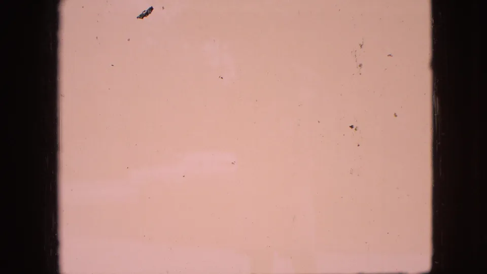 Faded 8mm frame from the Branson, Missouri clip with little visible scene detail, showing pink color shift, dust specks, and dark film borders.