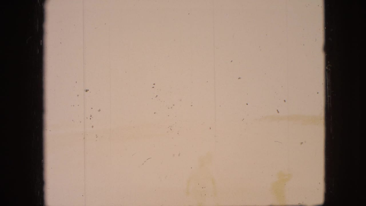 Mostly overexposed pale film frame with dust, scratches, and dark vertical border areas.