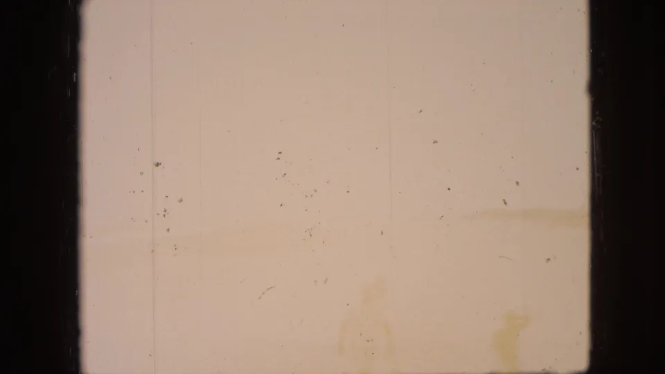 Faded 8mm frame from the Branson, Missouri clip with little visible scene detail, warm tinting, dust specks, and dark film edges.