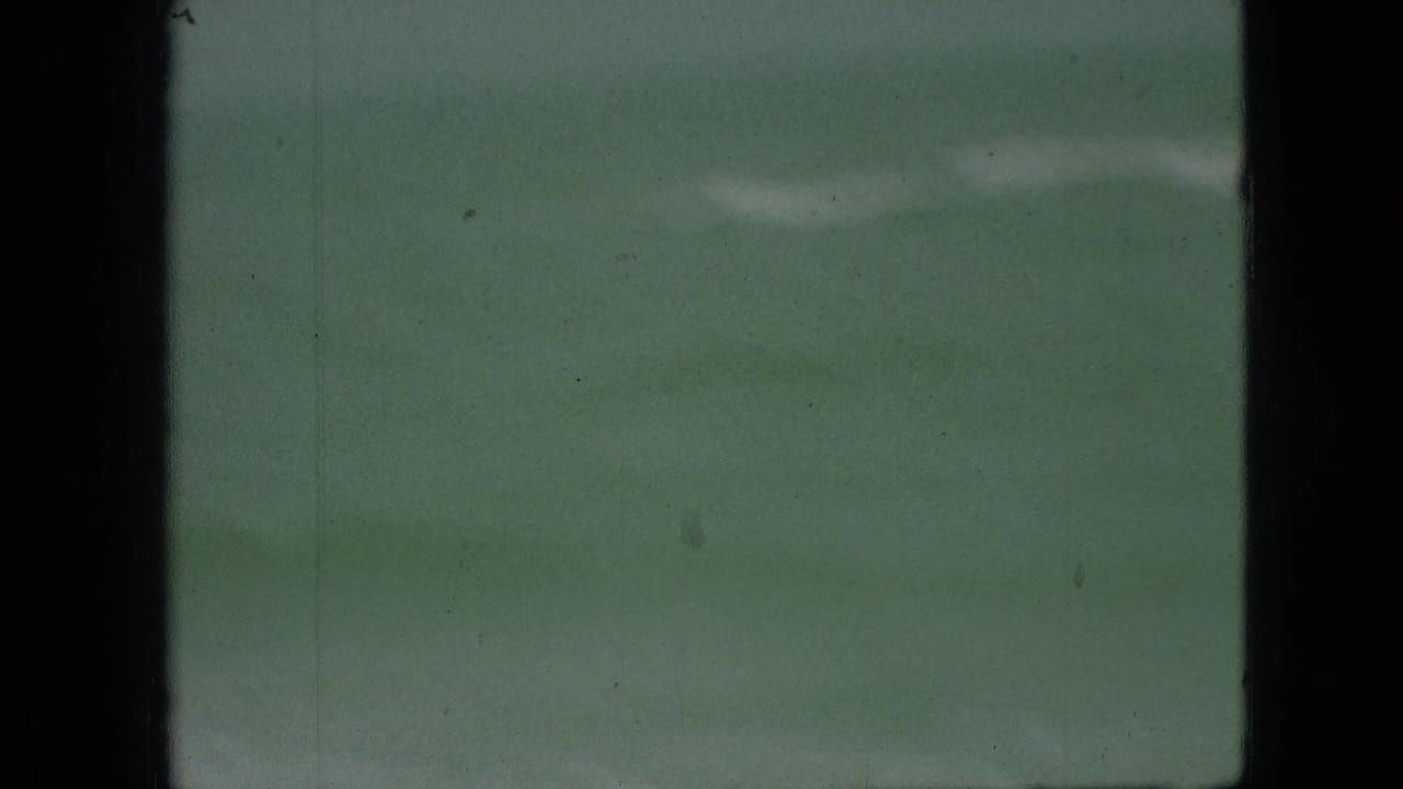 Flat green-blue water with faint white surf under soft light.