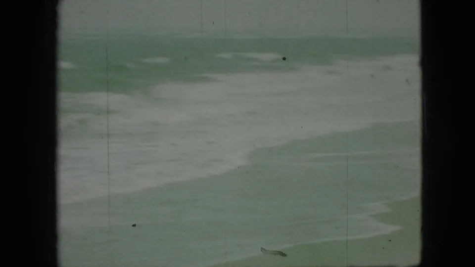 1968 8mm home-movie frame showing pale greenish-blue water and white foam bands, with dark gate edges and visible film wear.