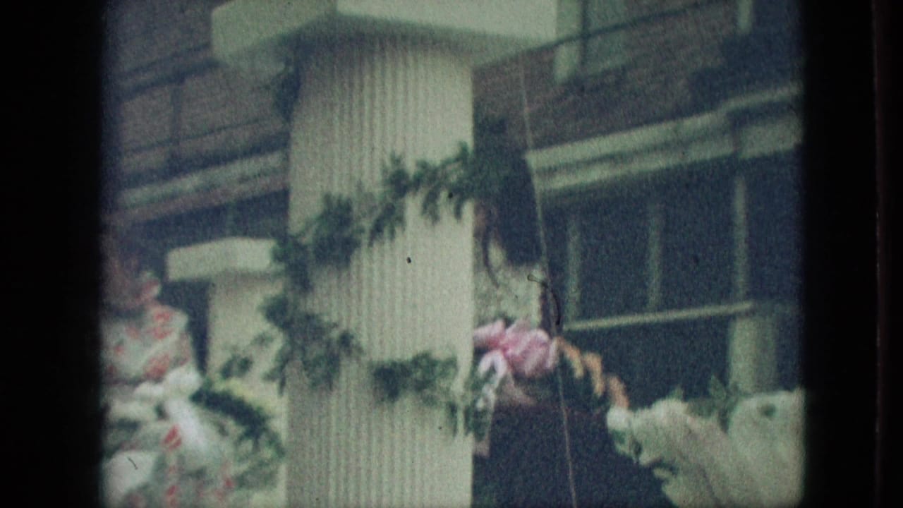 A white garlanded float pillar fills the center as seated parade participants and pink-wrapped decorations appear around it in the 1968 Branson, Missouri home-movie frame.