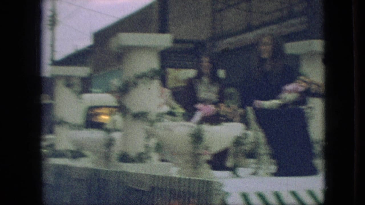 1968 Branson, Missouri parade footage showing a decorated float with women seated among flowers, white columns, and garland as it moves past the camera.
