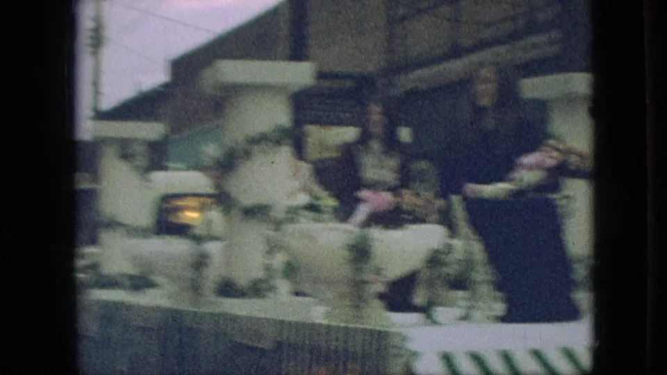 1968 Branson, Missouri parade footage showing a decorated float with women seated among flowers, white columns, and garland as it moves past the camera.