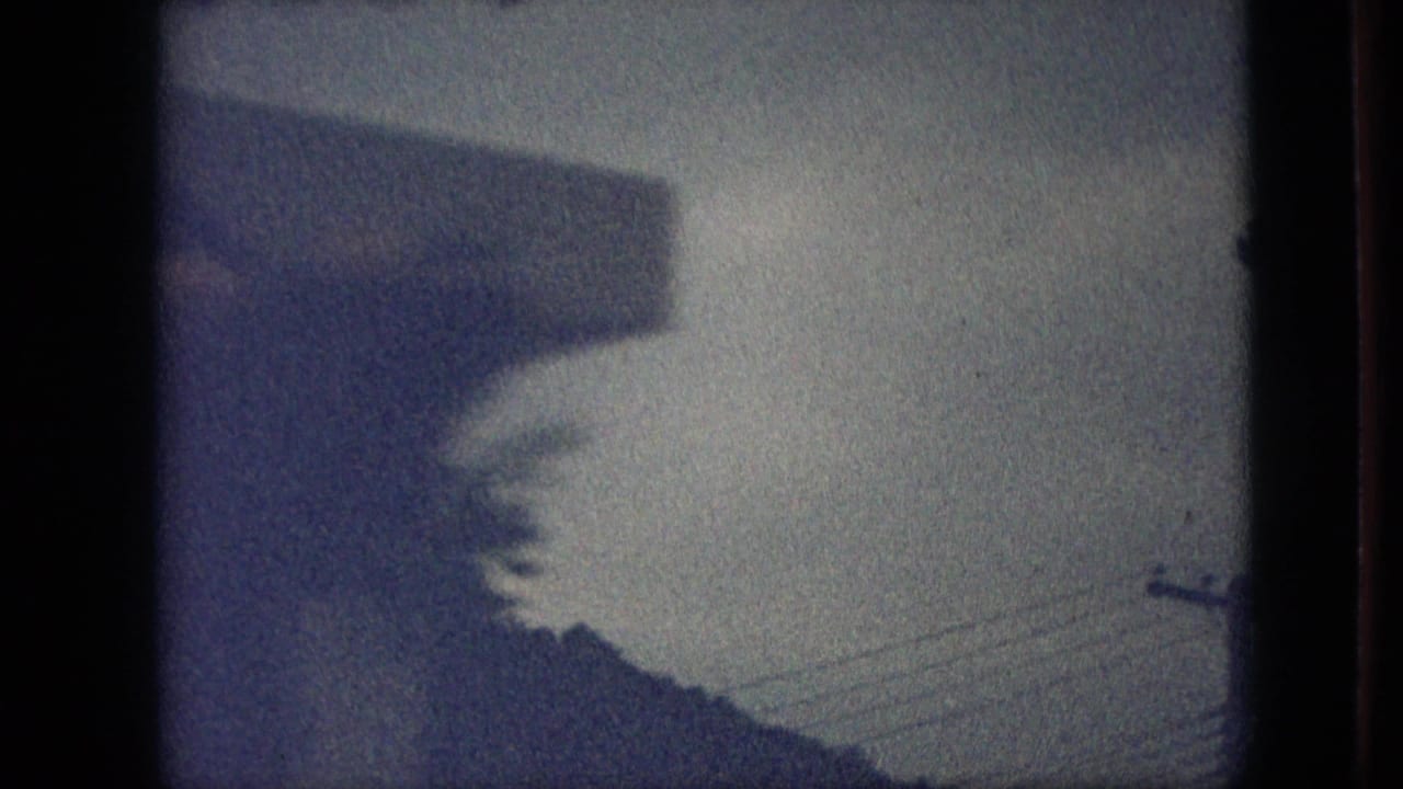 Blue-tinted 1968 Branson, Missouri 8mm frame showing a dim outdoor view with a roof edge, utility lines, tree shapes, and heavy home-movie vignetting.