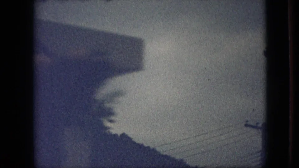 Blue-tinted 1968 Branson, Missouri 8mm frame showing a dim outdoor view with a roof edge, utility lines, tree shapes, and heavy home-movie vignetting.