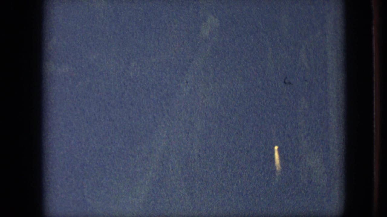 Mostly dark blue frame with film borders and a small yellow light streak at right.