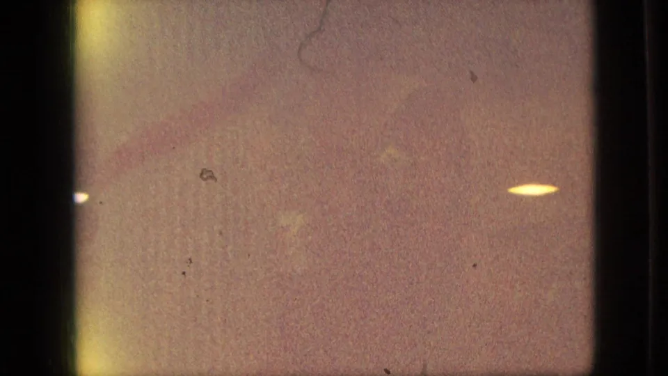 Final Branson, Missouri 1968 home-movie frame showing a warm, blurry low-light view with dust marks and a small bright parade or street light at right.