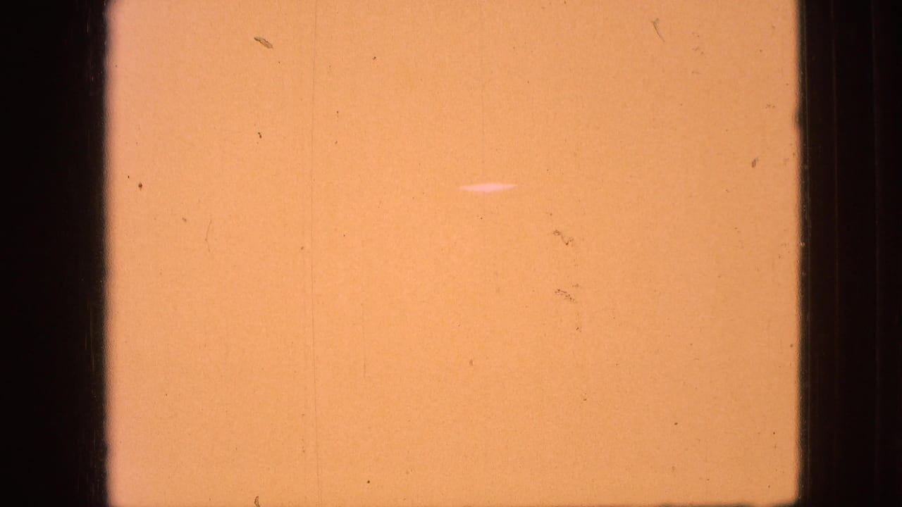 Aged 8mm film leader in an orange-yellow tone with dark frame borders, dust, and fine vertical wear marks.