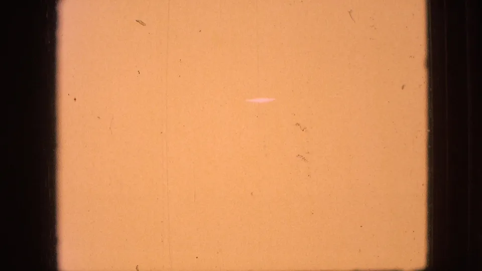 Aged 8mm film leader in an orange-yellow tone with dark frame borders, dust, and fine vertical wear marks.