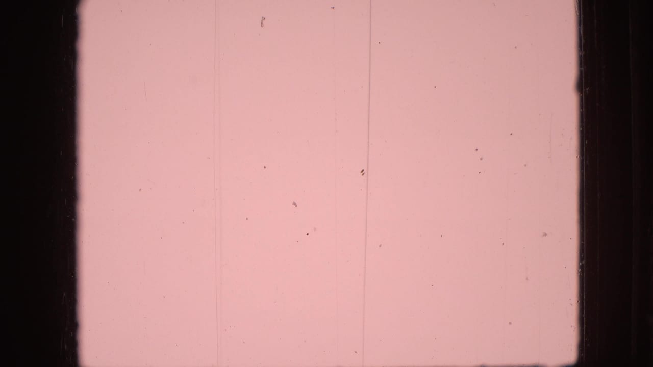Pink film leader with black vertical borders and surface marks.
