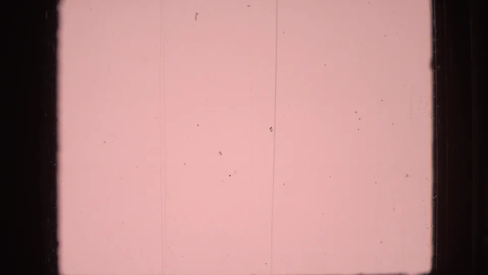 Pink-tinted 8mm leader frame with dark side borders, faint vertical lines, and small dust marks from the physical film scan.