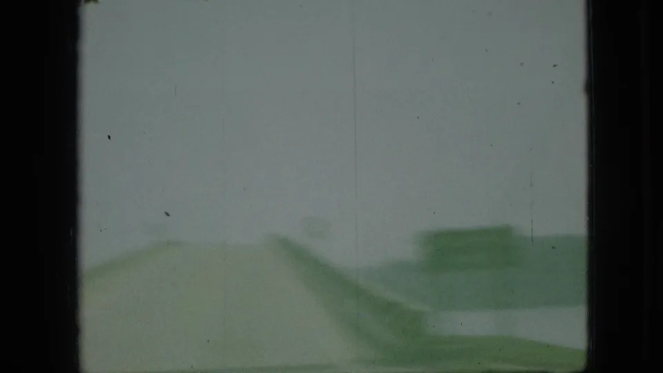 1968 Branson, Missouri 8mm frame showing a blurred moving-car view with an overcast sky, green roadside form, and heavy film-frame borders.