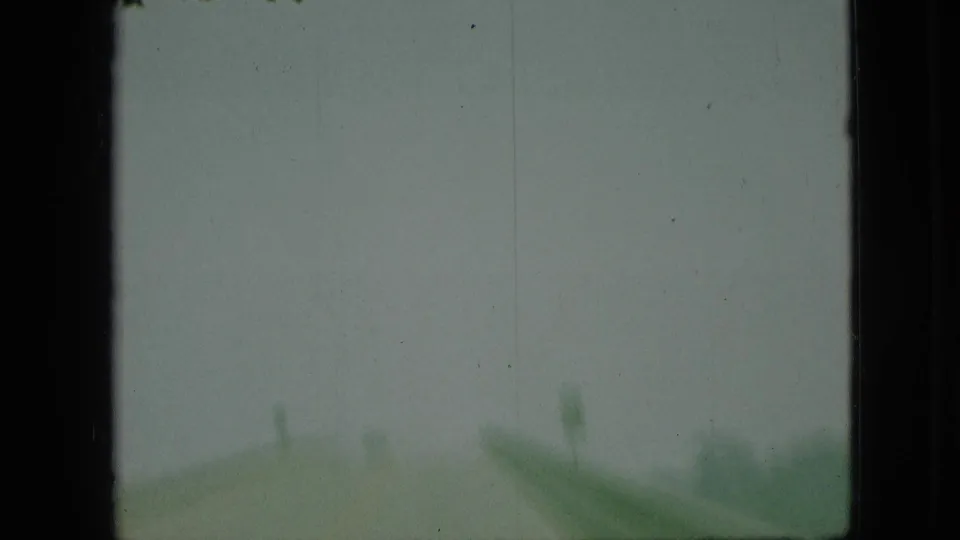 1968 Branson, Missouri 8mm frame with a soft moving-car view, gray sky, green roadside sign-like shape, and visible film wear.