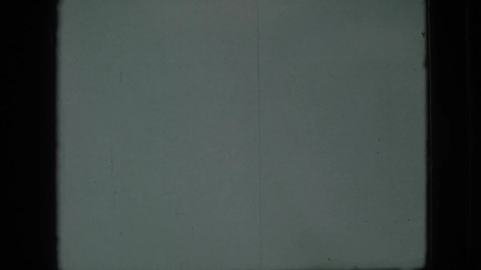 1968 Branson, Missouri 8mm frame showing a very soft gray-green view through dark vertical frame edges, with grain and faint surface marks dominating the scene.
